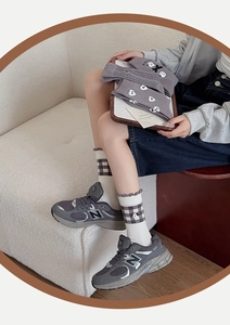 Detailed close-up of grey mid-calf socks with cute cartoon embroidery and ruffled edges