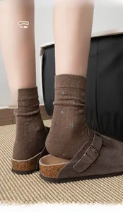 Détail de chaussettes en coton marron avec motifs floraux brodés et bords côtelés