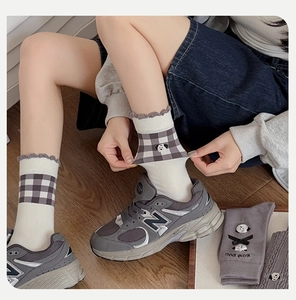 Close-up of grey plaid socks featuring cartoon puppy embroidery and black bow detail