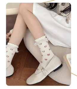 Detail of white cotton socks with red bow embroidery, pearl accents and lace trim