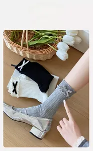 Detail of ballet style socks with velvet bows and ruffled edges on wooden floor