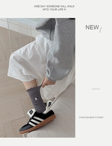 Detail of grey socks with cute bear embroidery and ruffle trim styled with sneakers