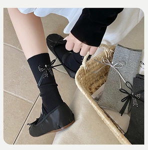 Détail de chaussettes grises côtelées avec nœud en strass et chaussures Mary Jane