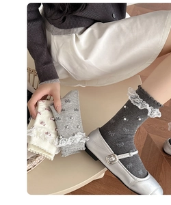 Detail of grey and beige lace ruffle crew socks with pearl beads and bow accents