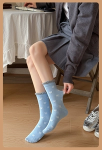 Détail de chaussettes bleu clair avec motif nœud blanc et bordures à volants gris