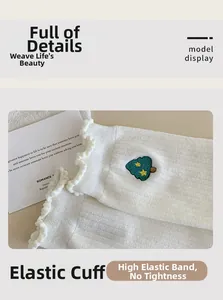 Close-up of white ribbed cotton socks with lettuce edge and green tree embroidery