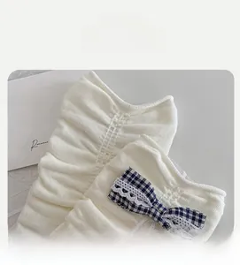 Detail of white knit socks with blue plaid bow, lace trim and elastic pleated cuffs