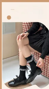 Détail de chaussettes grises avec nœuds en vichy noir et volants en dentelle fine