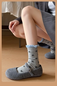 Détail de chaussettes grises avec nœuds noirs et bordure volantée bleue en maille