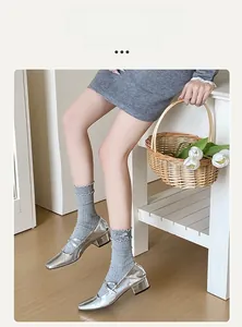 Detail of silver Mary Jane shoes with grey knit socks featuring bows and ruffle trim