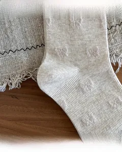 Detail of beige ribbed socks showing reinforced toe and heel with bow pattern jacquard