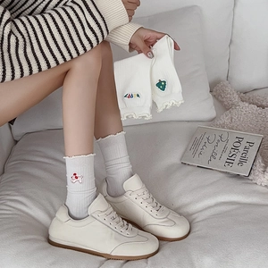 White crew socks with frill trim and cute cartoon embroidery in a cozy lifestyle setting
