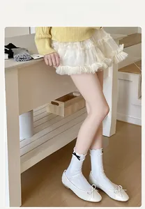 Detail of white ribbed crew socks with black bows and ruffled edges in ballet style