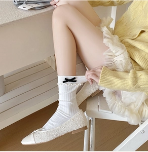 Close-up of white ribbed crew socks with double ruffles and cute black velvet bows