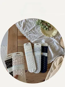Detail of five pairs of cotton knit crew socks with jacquard polka dots on a rustic wooden table