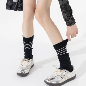 Two-piece style black crew socks with white stripes paired with silver sneakers