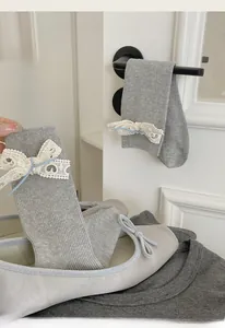 Calze grigie a maglia con fiocchi di pizzo e nastri azzurri appese alla maniglia