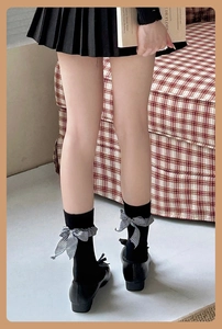 Détail de chaussettes mi-mollet noires avec volants à carreaux et nœud sur un mannequin