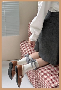 Détail de chaussettes blanches à côtes avec nœuds à carreaux et chaussures Mary Jane