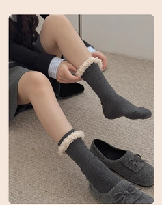 Close-up of dark grey ribbed crew socks with cream faux fur trim on a woven rug