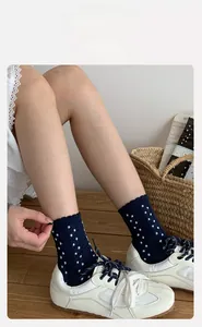 Detail of dark blue polka dot crew socks with ruffled cuffs and white canvas shoes