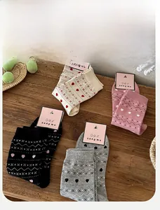 Detailed flat lay of Fair Isle crew socks in white, pink, grey, and black on a wood table