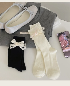 Dettaglio di calze lolita con fiocco in pizzo nei colori nero e bianco crema