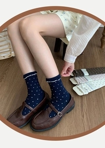 Detail of navy blue polka dot socks with wavy edges paired with vintage Mary Jane shoes