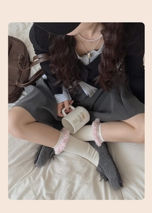 Detail of white knit socks with pink plush lace trim and grey felt flats