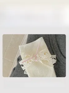 Dettaglio del polsino elastico su calze bianche con pizzo e piccolo fiocco rosa