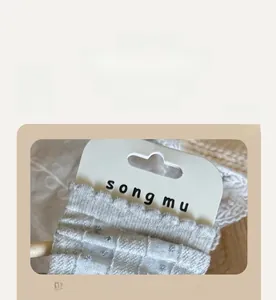 Detailed close-up of light gray cotton socks with scalloped lace cuffs and polka dot texture