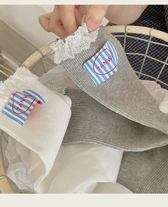 Close-up of women's cotton socks with lace trim and woven logo label in a basket
