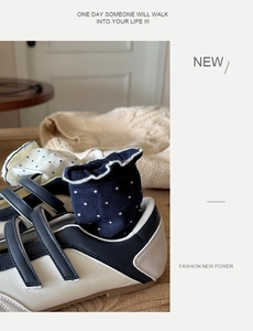 Detail of dark blue polka dot ruffle socks paired with black and white Mary Jane shoes