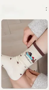 Detail der Dackel-Stickerei auf elastischen beigen Socken mit Polka Dots