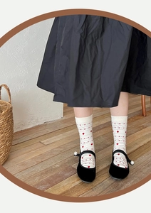 Detail of Fair Isle socks with red hearts and pearls on Mary Jane shoes in a home setting