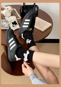 Dettaglio del ricamo 3D con animali su calze di cotone nere abbinate a sneakers nere