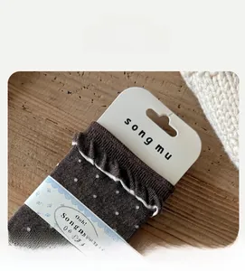 Detail of high-elasticity sock cuff with white lace ruffle edge and navy blue polka dots