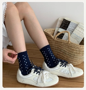 Detailed view of knitted cotton socks with scalloped edges and white polka dots pattern