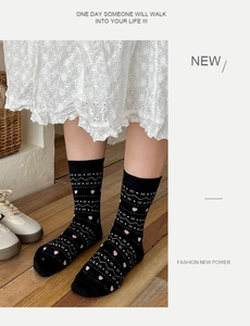 Detail of Fair Isle crew socks with pink hearts and white geometric patterns on black cotton