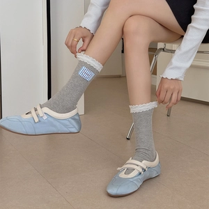 Gray knitted socks with white lace trim and blue label paired with ballet flats