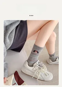 Detail einer grauen Baumwollsocke mit süßem Hundemuster und bunten Streifen und Schuhen