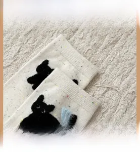 Dettaglio dei calzini bianchi con pois arcobaleno, ricamo di gatto e polsino elastico