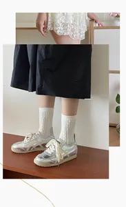 Gros plan de chaussettes blanches à torsades avec des baskets argentées brillantes