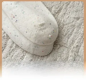 Dettaglio della punta rinforzata su calze in maglia bianco avorio con pois colorati