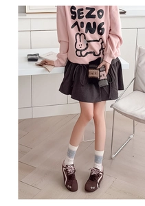Close-up of gray Fair Isle crew socks paired with a pink sweatshirt and pleated skirt