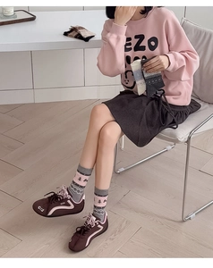 Detail view of pink and grey Fair Isle knit socks with tree patterns worn by a model