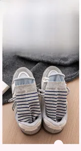 Detail of gray and blue striped socks with rolled edges inside a casual gray sneaker