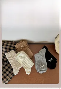 Détail de chaussettes en tricot torsadé avec perles et nœuds en cinq coloris assortis