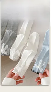 Detail of knit socks with lace rabbit ear bows, pearls, and delicate ruffled edges
