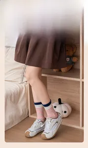 Classic white retro sneakers with red and white striped crew socks in a cozy indoor setting